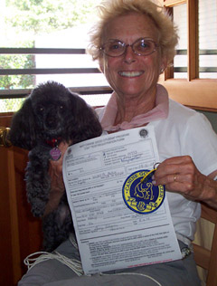 A women holding a small dog and a certificate